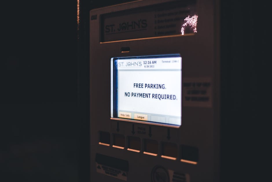 Close-up of a digital parking meter displaying the message 'FREE PARKING. NO PAYMENT REQUIRED.' in black text on a white background, with illuminated buttons below and a dark background around the met